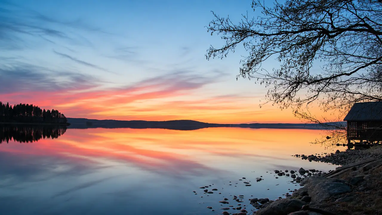 Auringonlaskun värit heijastuvat tyynestä järvestä Luhangan rantamaisemassa.